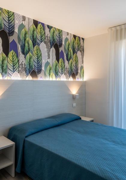 Modern room with leaf wallpaper and double bed.