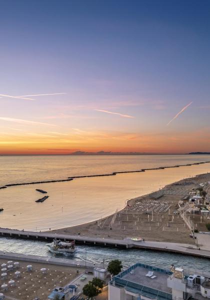 Tramonto sul mare con ruota panoramica e spiaggia.