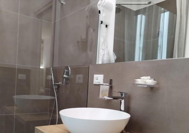 Modern bathroom with round sink, shower, and hairdryer.