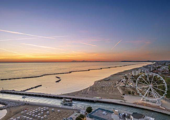 Sonnenuntergang über dem Meer mit Riesenrad und Strand.