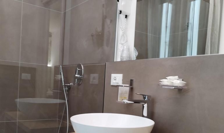 Salle de bain moderne avec lavabo rond, douche et sèche-cheveux.