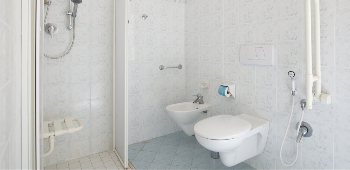 Bagno accessibile con doccia, wc, bidet e maniglioni di supporto.