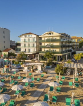 Balcone con vista sul mare e spiaggia attrezzata con lettini e ombrelloni.