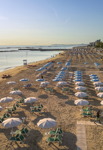 Spiaggia al mattino con ombrelloni e mare calmo.