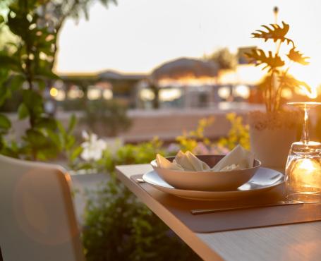 Table dressée au coucher du soleil avec verres et assiettes.