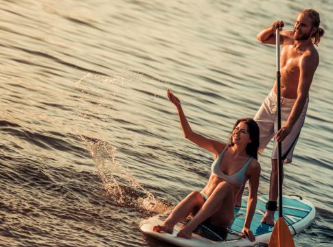 Due persone fanno paddleboarding al tramonto sull'acqua.