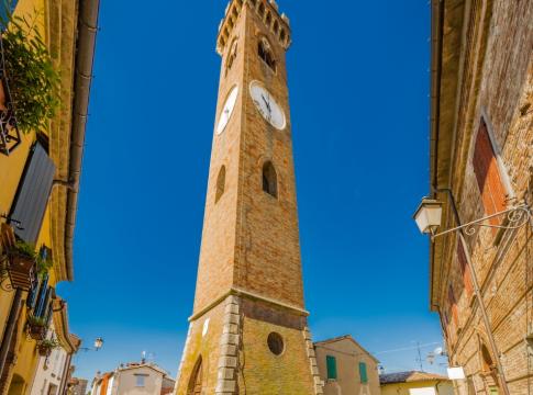 Torre dell'orologio in un borgo con cielo azzurro.