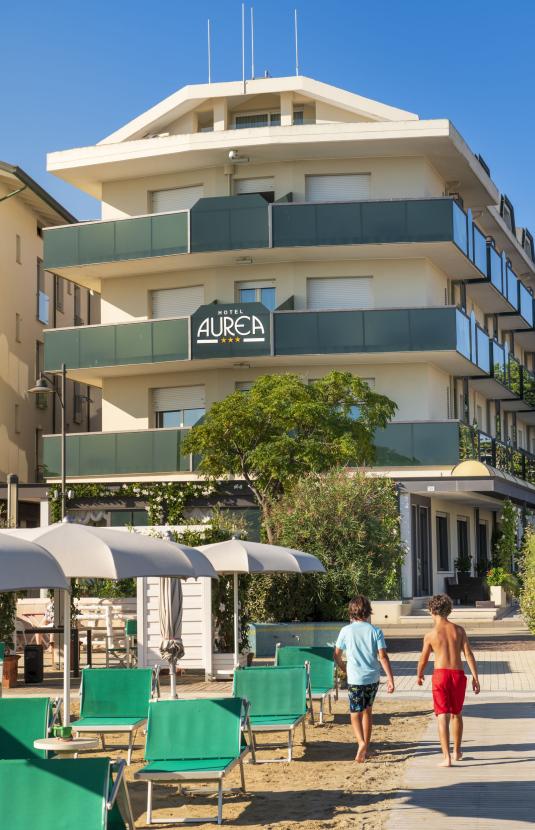 Hotel Aurea nahe dem Strand mit grünen Liegen.