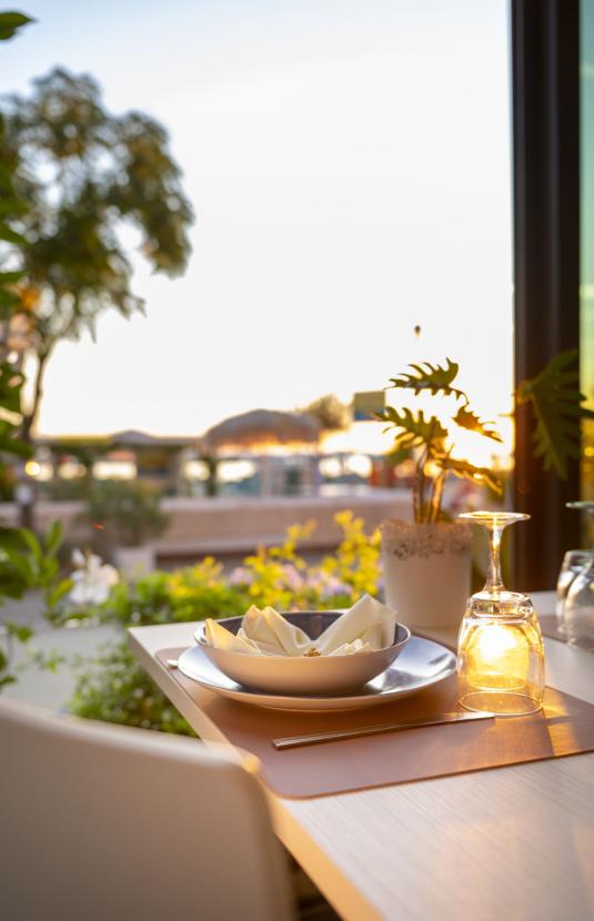 Tavolo apparecchiato al tramonto con piatti e bicchieri.