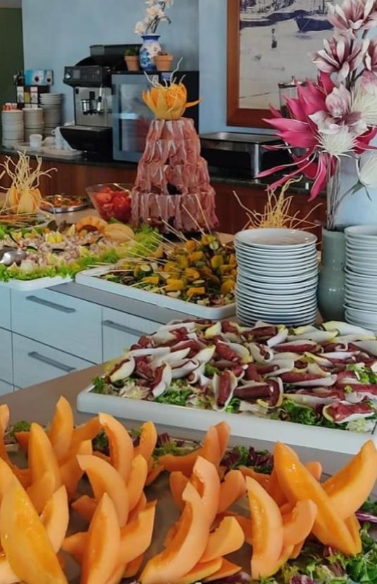 Buffet con frutta, verdure e salumi in un ambiente elegante.