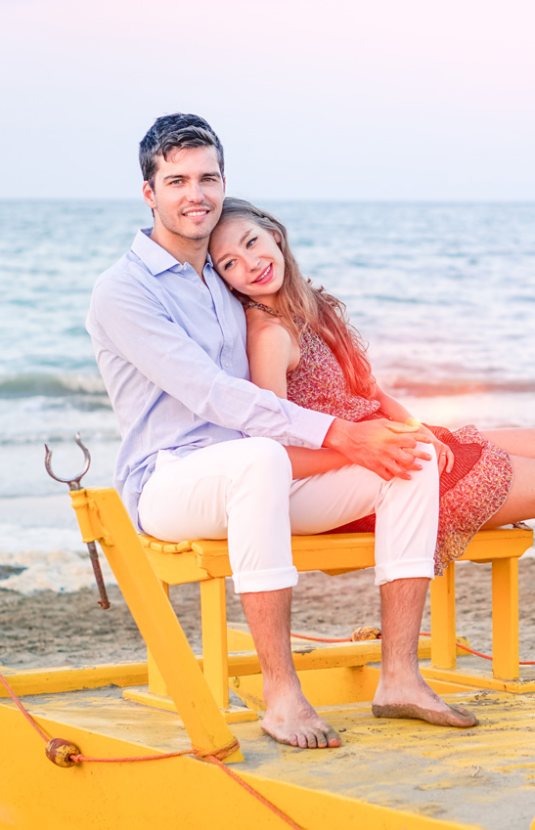 Coppia felice seduta su un pedalò giallo al mare.