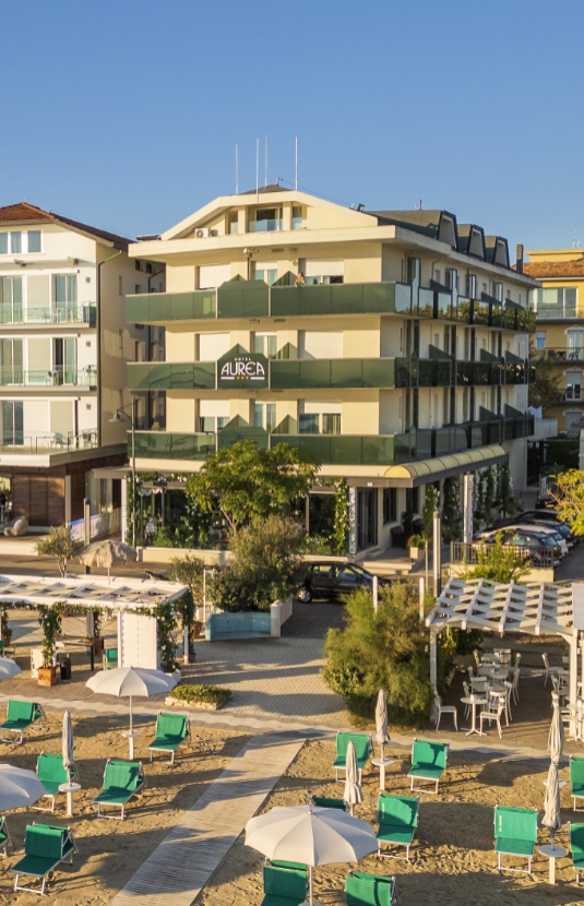 Hotel moderno con balconi, bandiere internazionali e parcheggio, situato in una zona urbana.