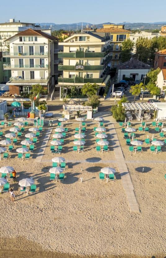 Spiaggia con ombrelloni e edifici sullo sfondo.