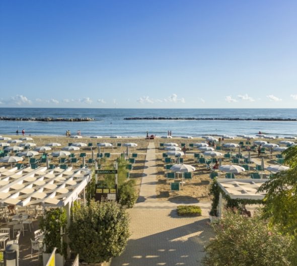 Spiaggia all'alba con ombrelloni chiusi e mare calmo.