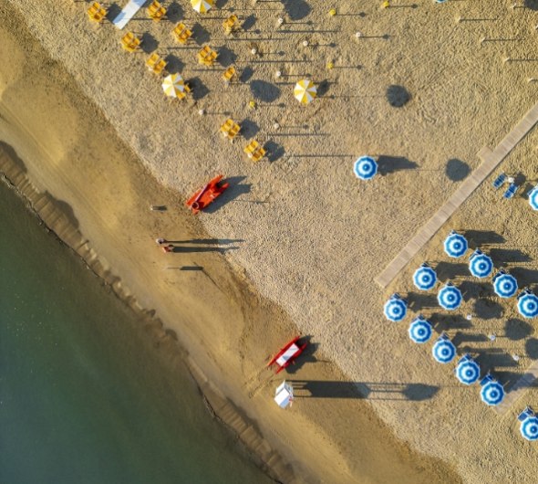 Vista mare da una finestra con spiaggia e barriere frangiflutti.