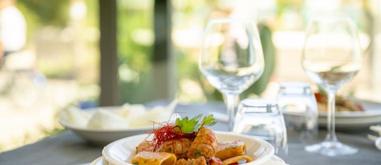 Piatto di pasta con salsiccia e guarnizione, tavola apparecchiata.